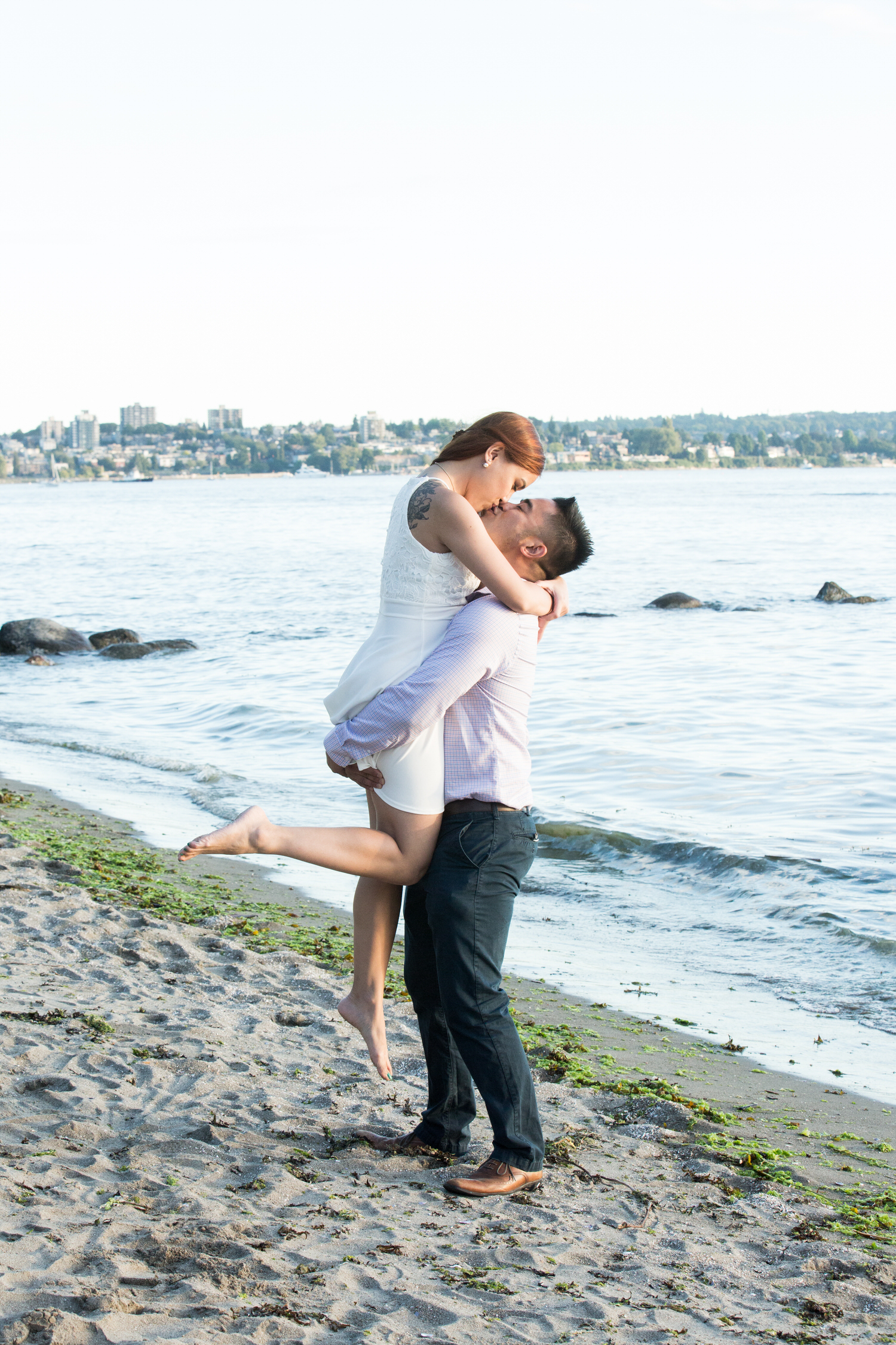 Boy lifting girl while kissing at Second beach in Stanley park by Vancouver wedding photographer THIS IS IT STUDIOS