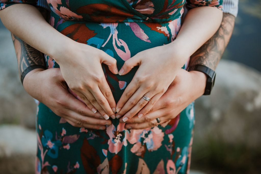 man and his pregnant wife created a heart with their hand for their upcoming baby.