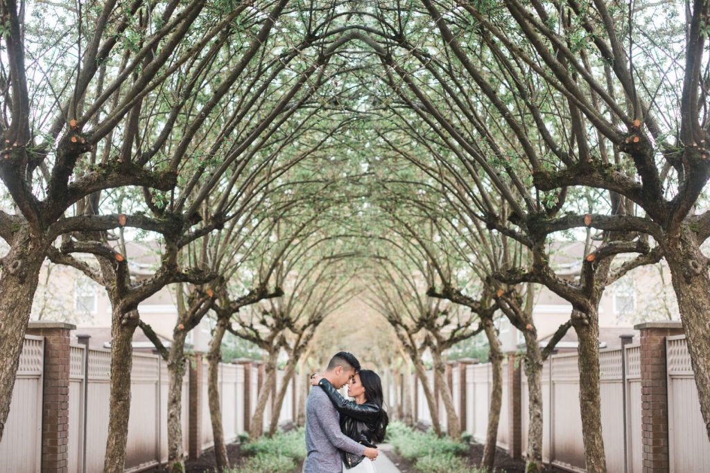 Unique engagement session of couple holding each other against a line of trees