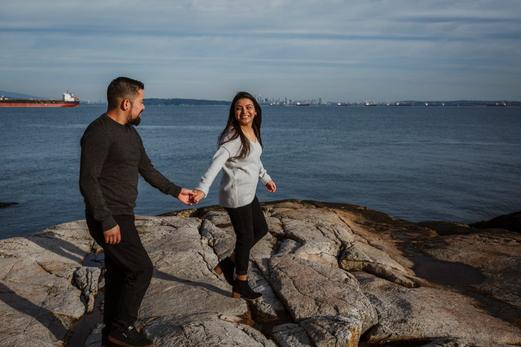 Lighthouse engagement session of couple casually walking on the rocks