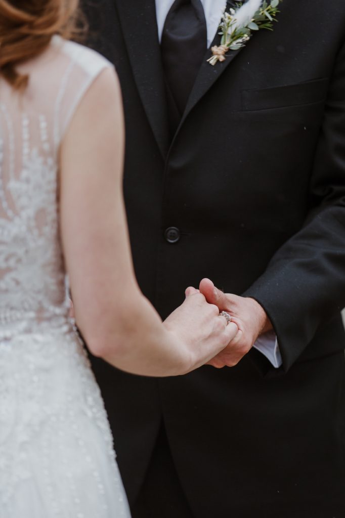 candid photo of Bride and groom holding hands