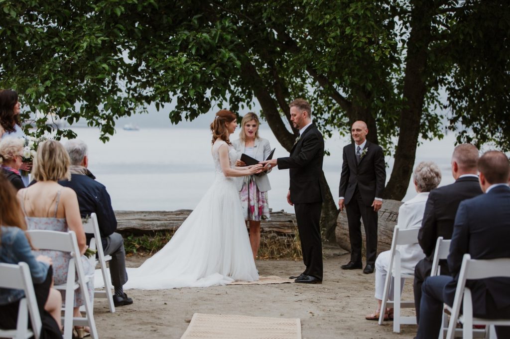 candid photo of bride putting on the ring on the groom in spanish banks