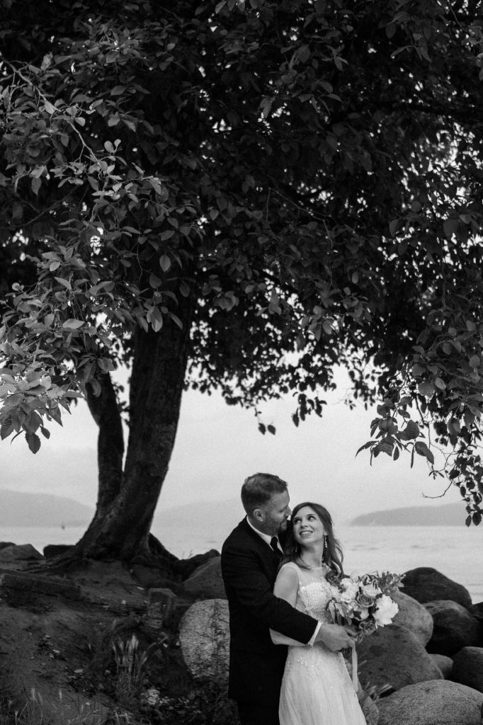 Black and white candid photo of the bride and groom hugging and smiling at each other in spanish banks