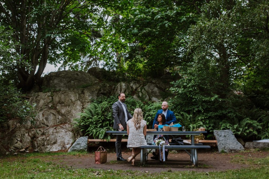 Wide angle photo of the bride and groom candidly hanging out with their witnesses during their surprise picnic