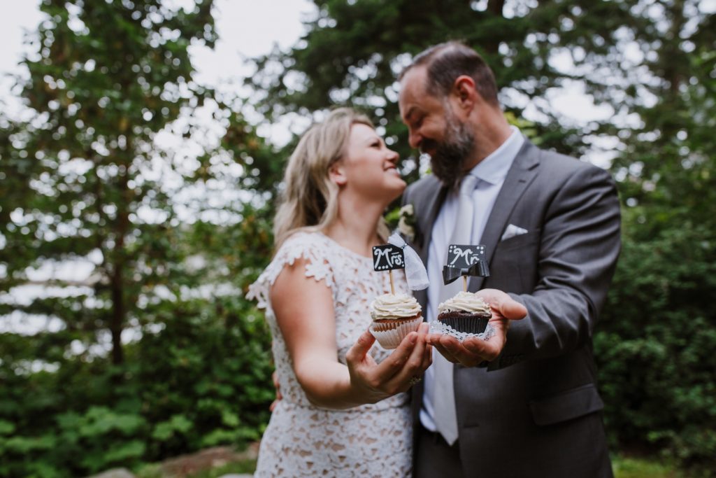 Bride and groom holding the mr and mrs cupcakes